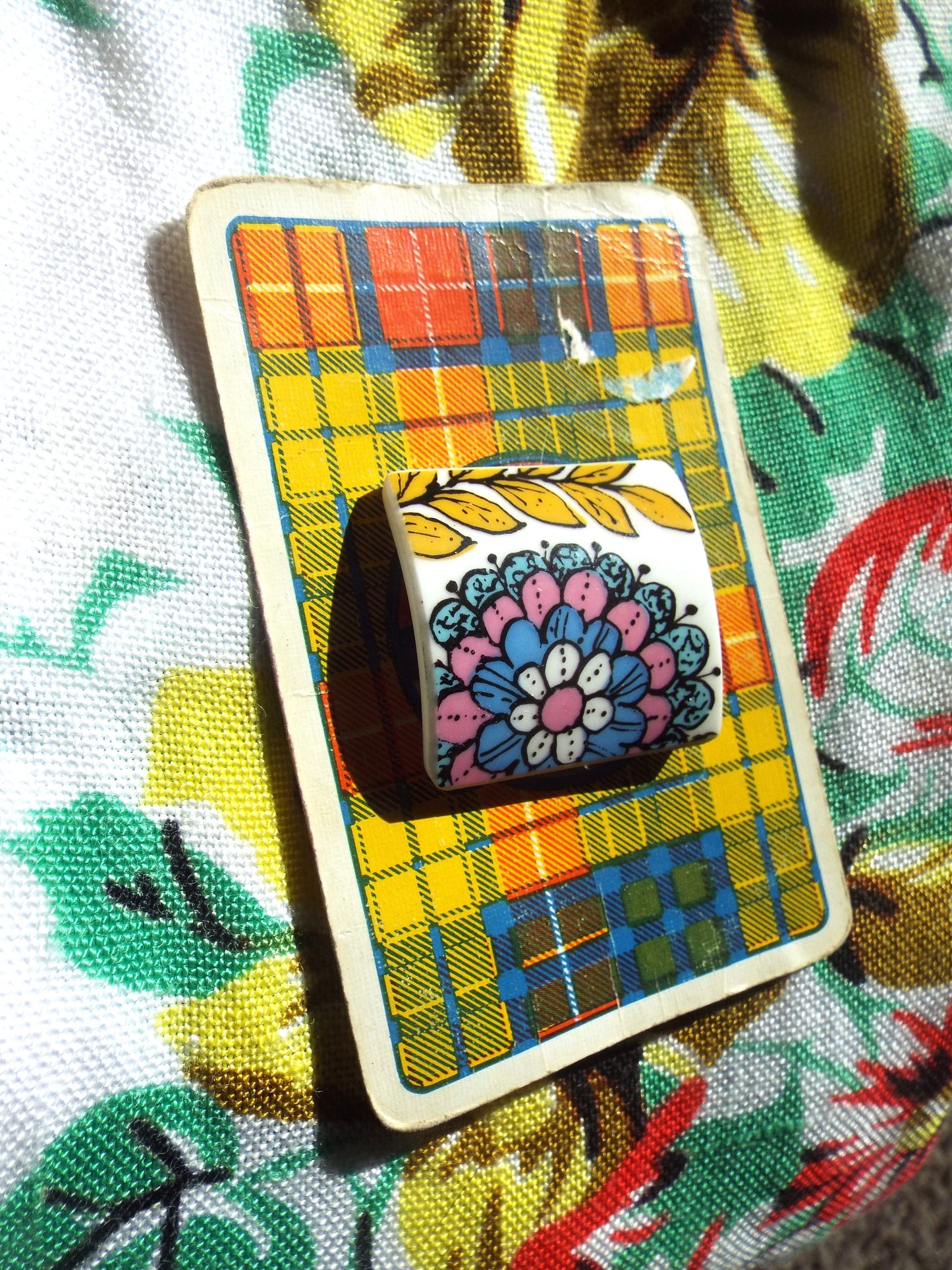 NEW Upcycled Ceramic Brooch - Funky Floral Design on tartan card, against a leafy backdrop.