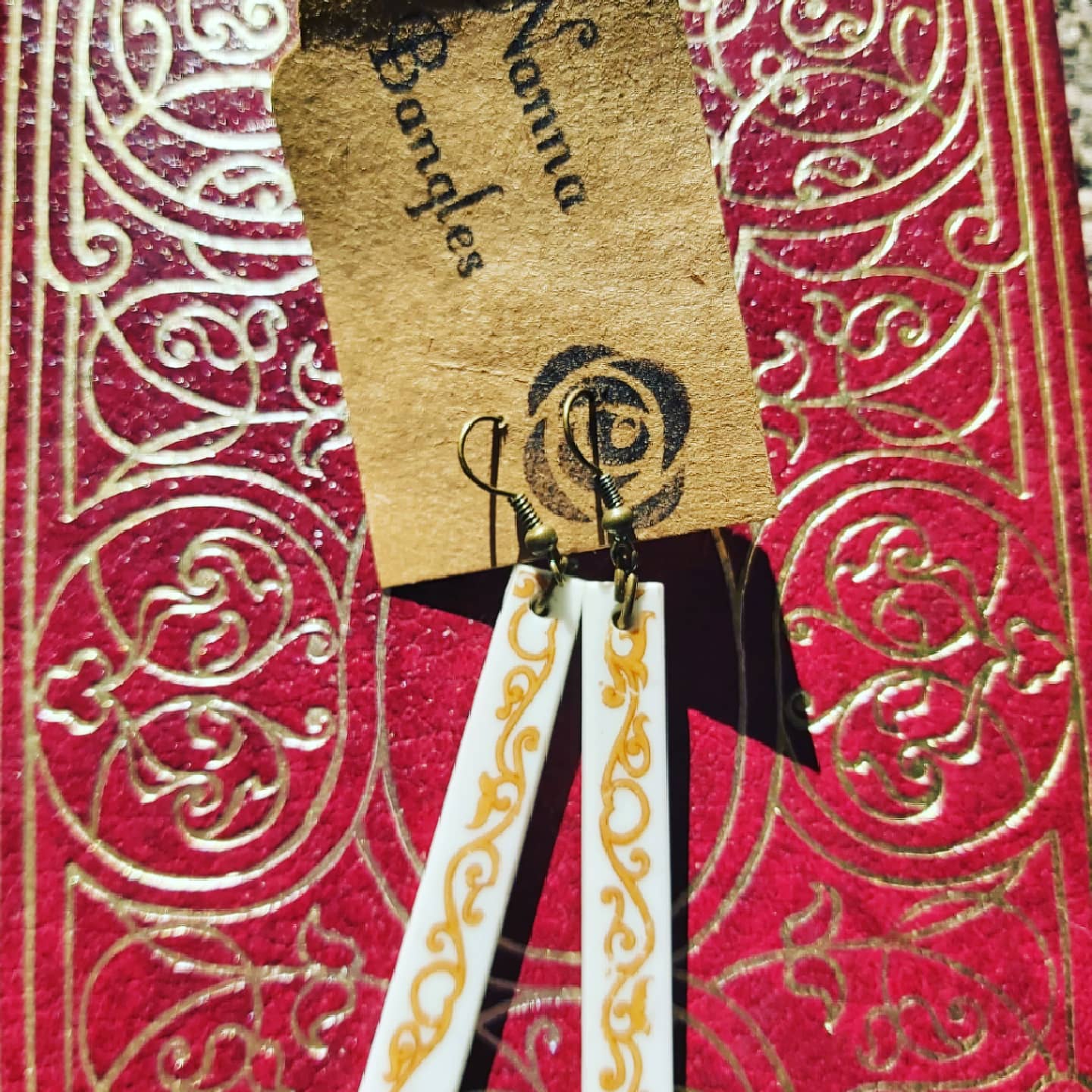 NEW Upcycled Ceramic Earrings - Long With Scroll Design on Nanna Bangles-branded card, against a red and gold-detailed backdrop.