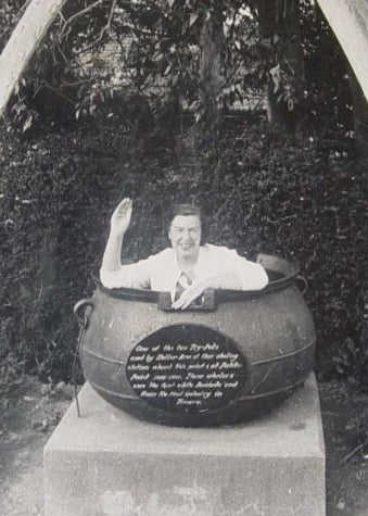 Old black and white photo of the original Nanna Bangles, goofily posing in a large pot her her hand up.