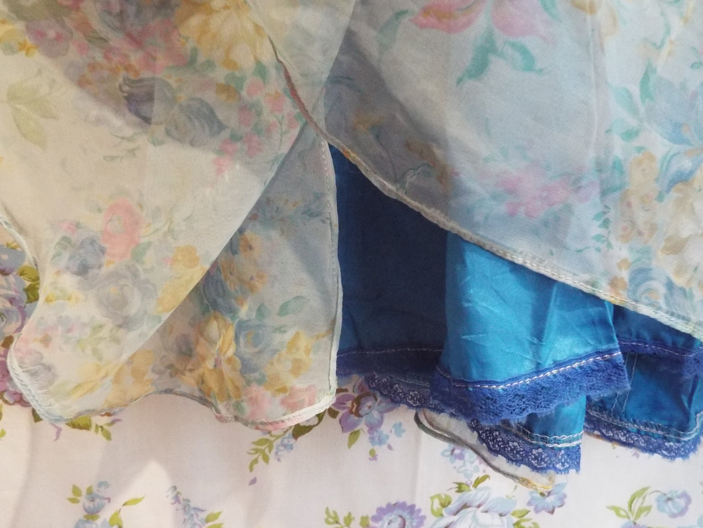 1970s Maxi Dress (S-M) with light blue floral patterned fabric and puffy sleeves, against patterned fabric with blue and purple roses.
