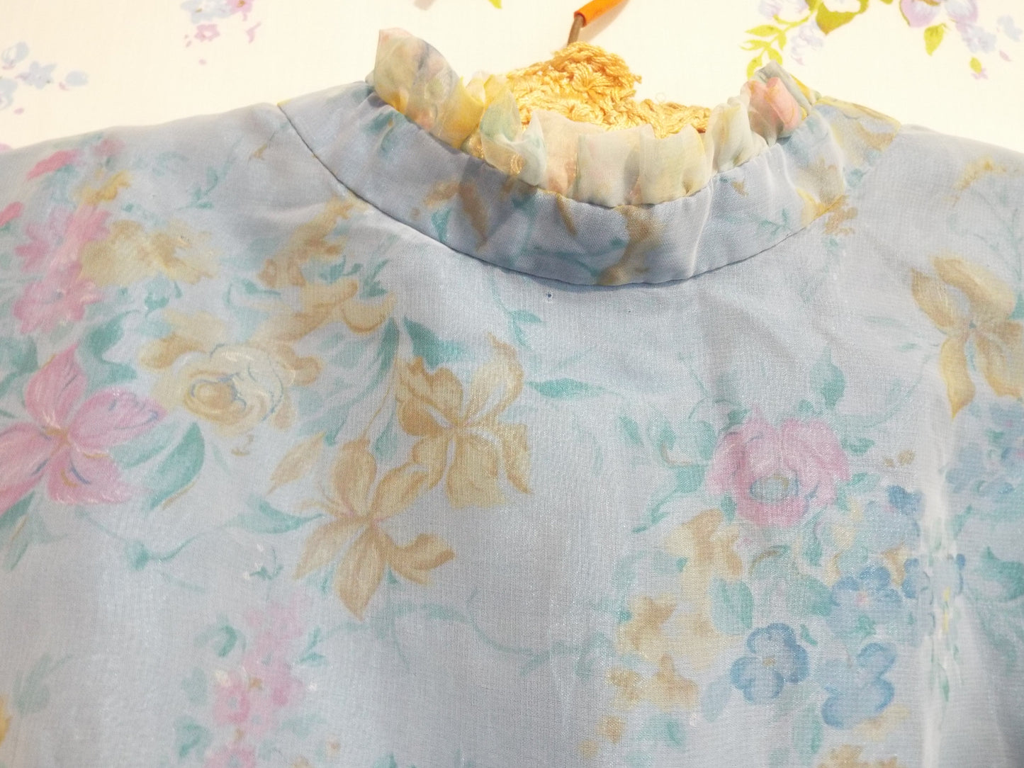 1970s Maxi Dress (S-M) with light blue floral patterned fabric and puffy sleeves, against patterned fabric with blue and purple roses.