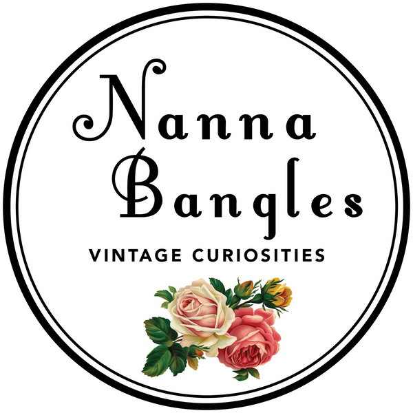 Logo of Nanna Bangles. A double-lined black circle encompassing the words 'Nanna Bangles Vintage Curiosities' in a scripted font. Full colour rose illustrations complete the design.