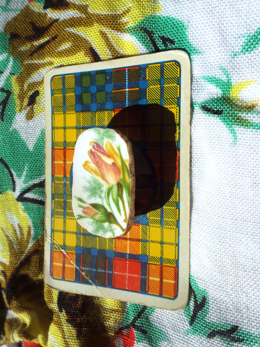 Pre-Loved Bone China Brooch on tartan card, against leafy backdrop.