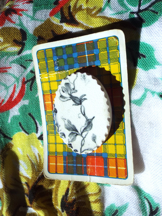 Pre-Loved Ceramic Brooch - Antique Floral on tartan card, against a leafy backdrop.